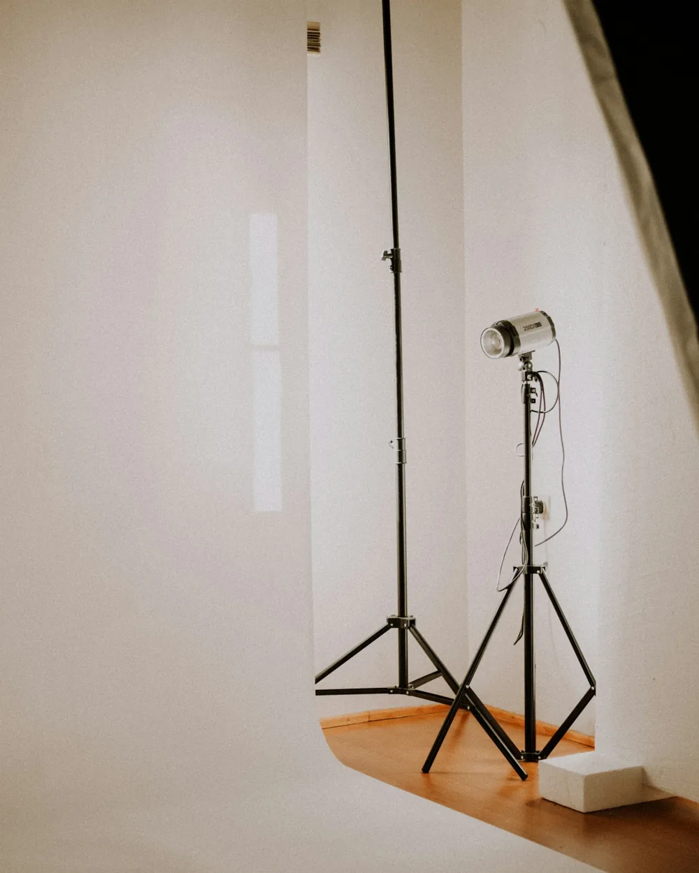 Foco de flash de estudio sobre trípode junto a un fondo de papel continuo claro que cae y curva hacia el suelo